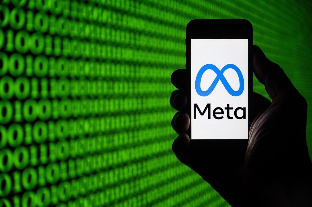 Meta logo on a phone against green and black coding background.